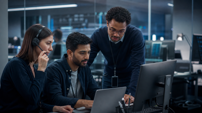 Three IT support professionals collaborating at a workstation